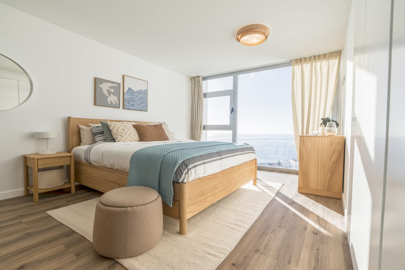 Fotografía de arquitectura de un dormitorio principal moderno en Almuñécar con cama de madera, luz natural y vistas panorámicas al mar Mediterráneo.
