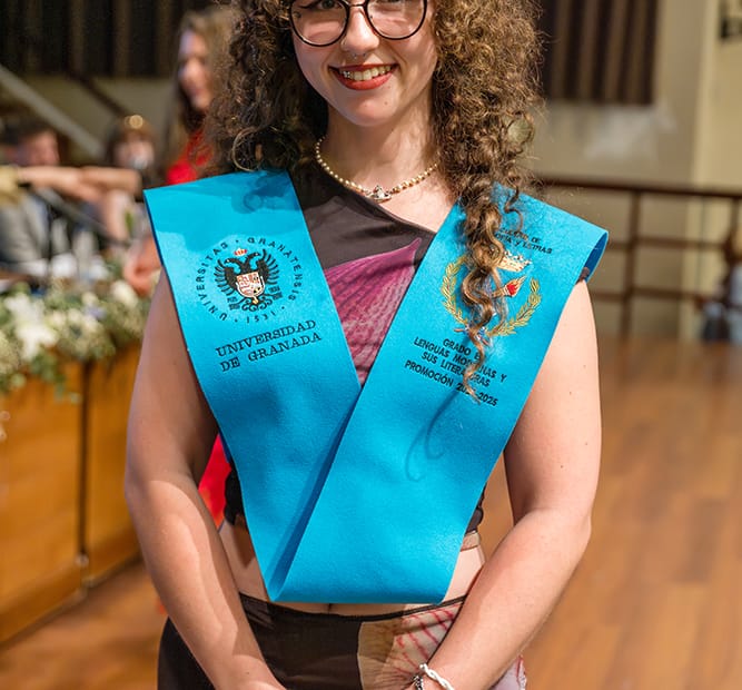 Retrato de una joven graduada de la Universidad de Granada con la banda de su titulación. Reportaje fotográfico de graduación por IMG Creativos.