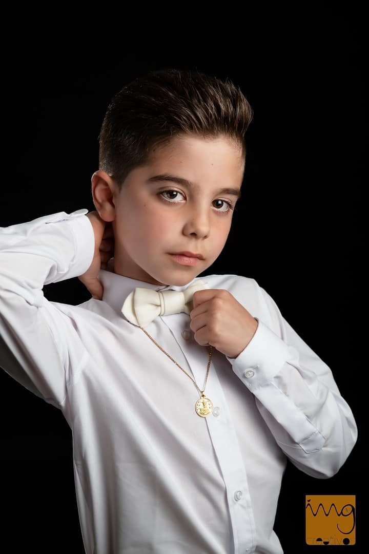Fotografía de Comunión en estudio con fondo negro y pose dandy