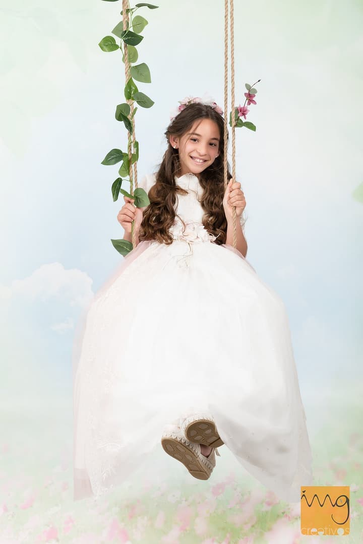Fotografía de Comunión en estudio con columpio y fondo insertado.