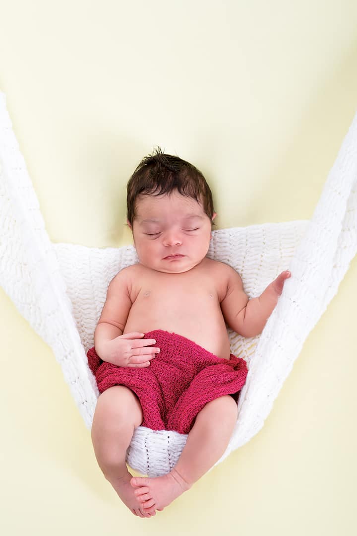 Fotografía de recién nacido en columpio con fondo amarillo