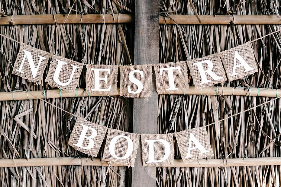 A close-up of a rustic wedding banner with burlap letters on a straw backdrop.
